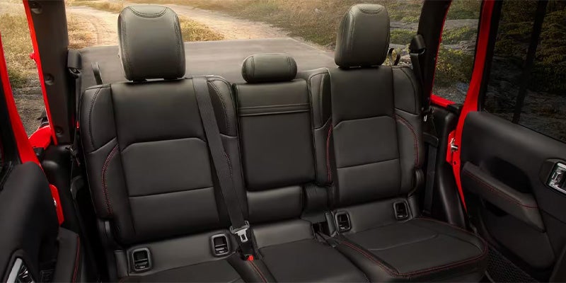 Rear seating area of Jeep Gladiator featuring three black leather seats with red stitching