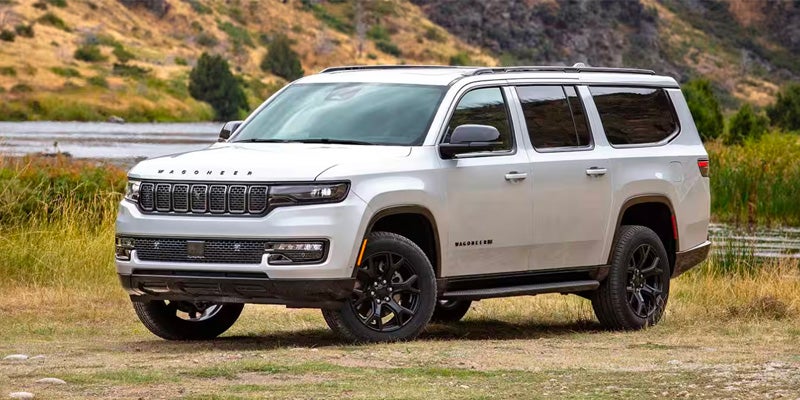 White Wagoneer SUV parked on a dirt path with rocky hills